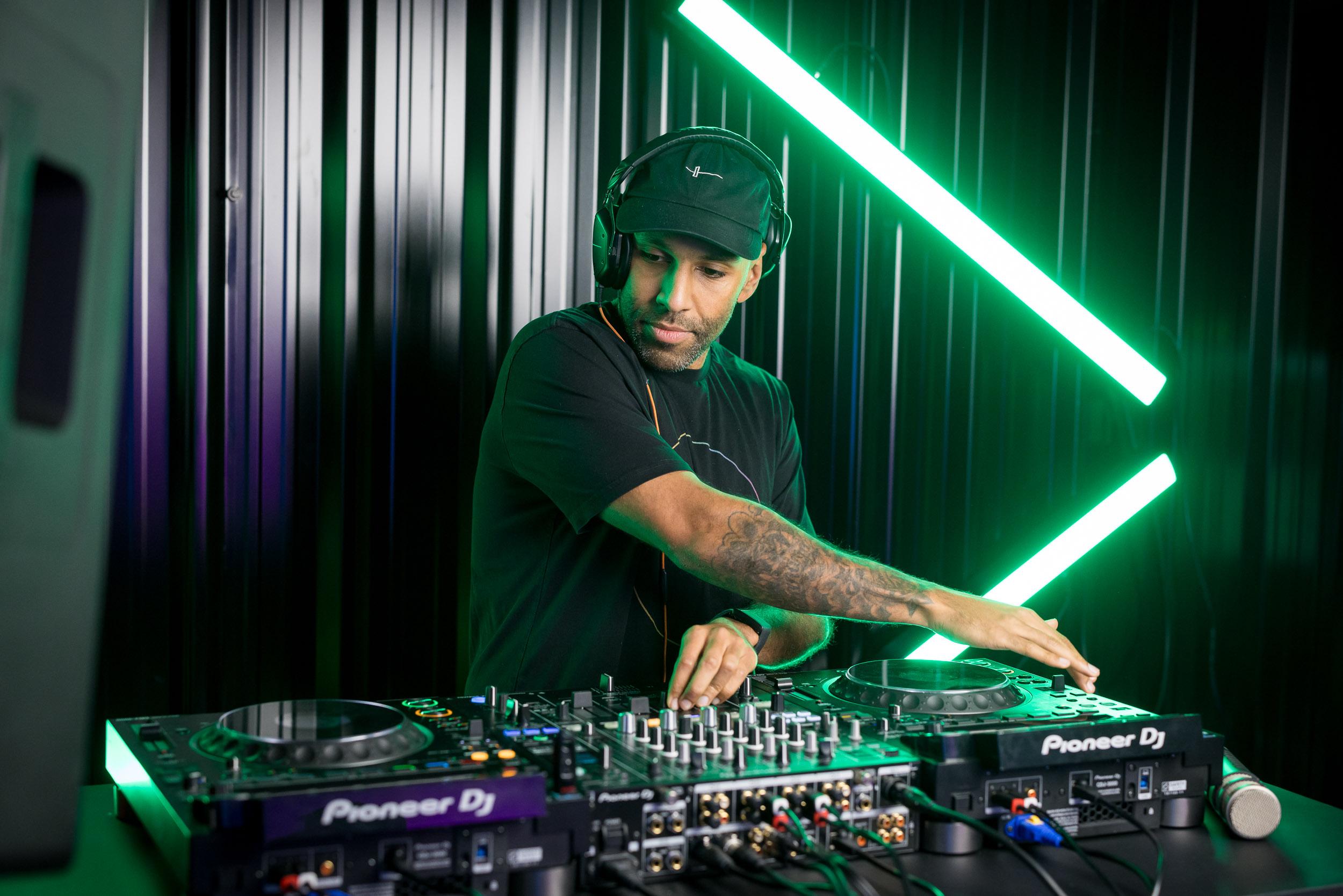 A Crossfader DJ mixing on Pioneer DJ CDJs under green studio lighting